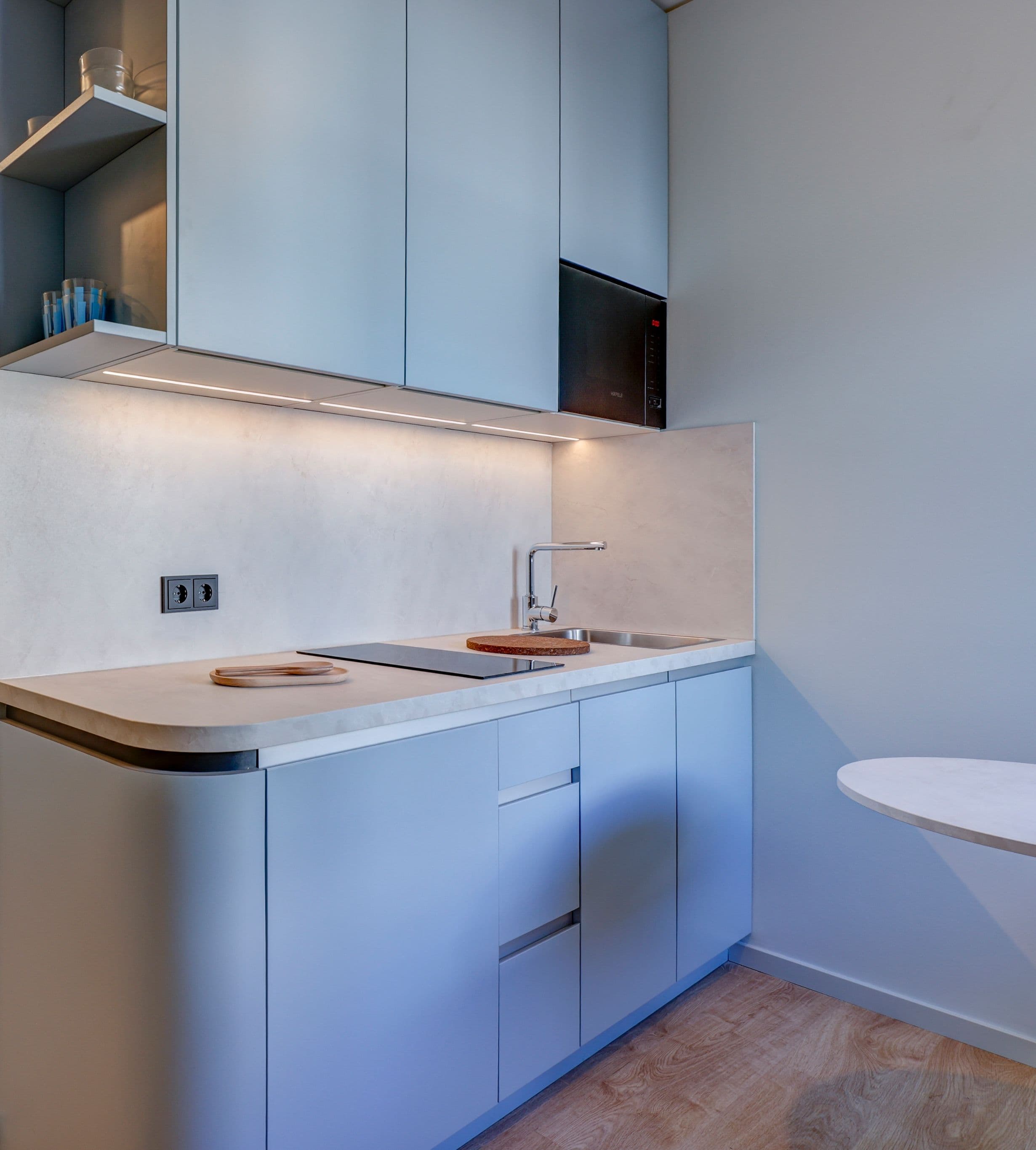 Studio Standard: Hellblaue Küche mit Herdplatten, Mikrowelle und Spülbecken.