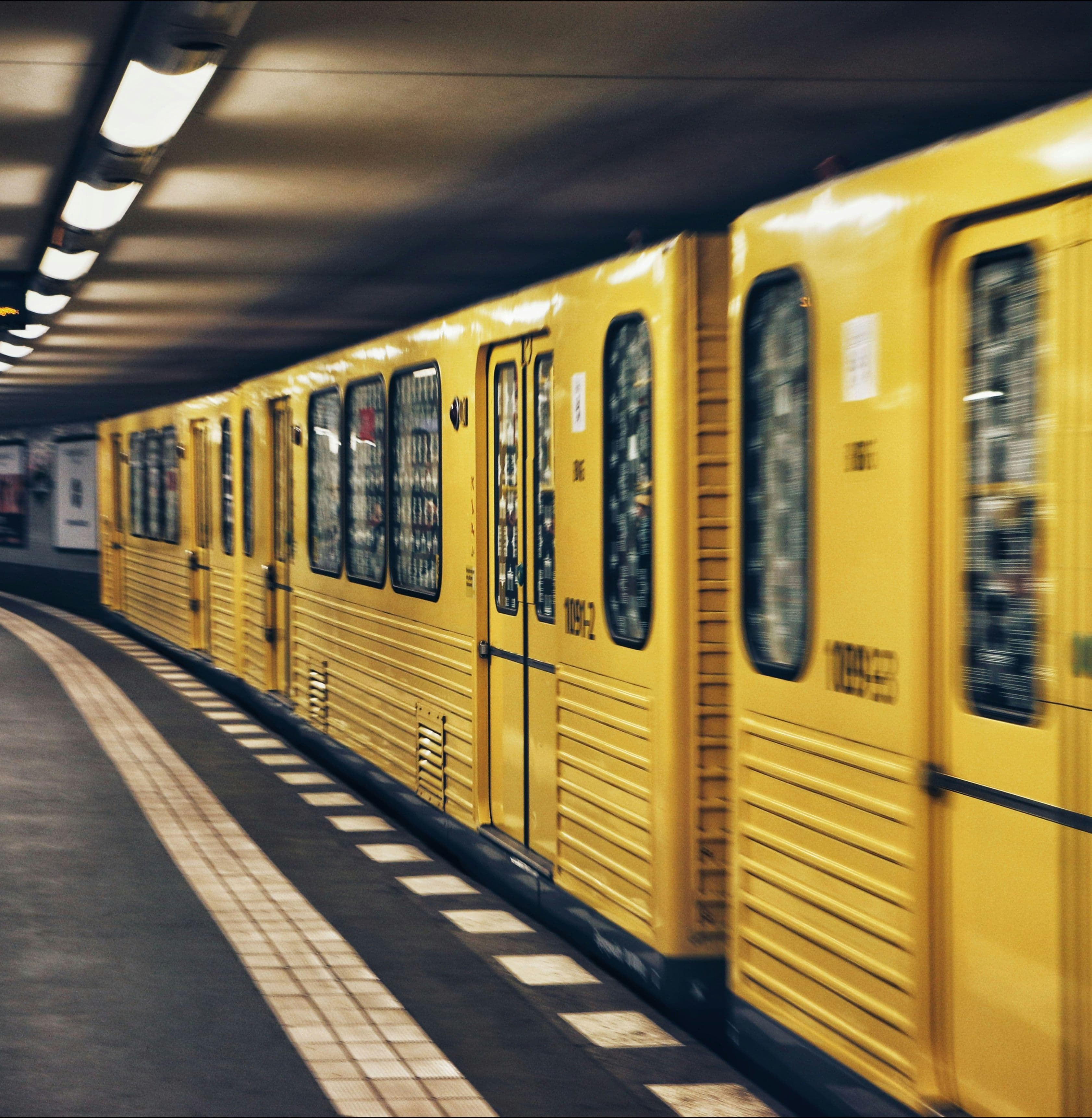 Gelbe Berliner U-Bahn fährt mit Bewegungsunschärfe in einen U-Bahnhof ein