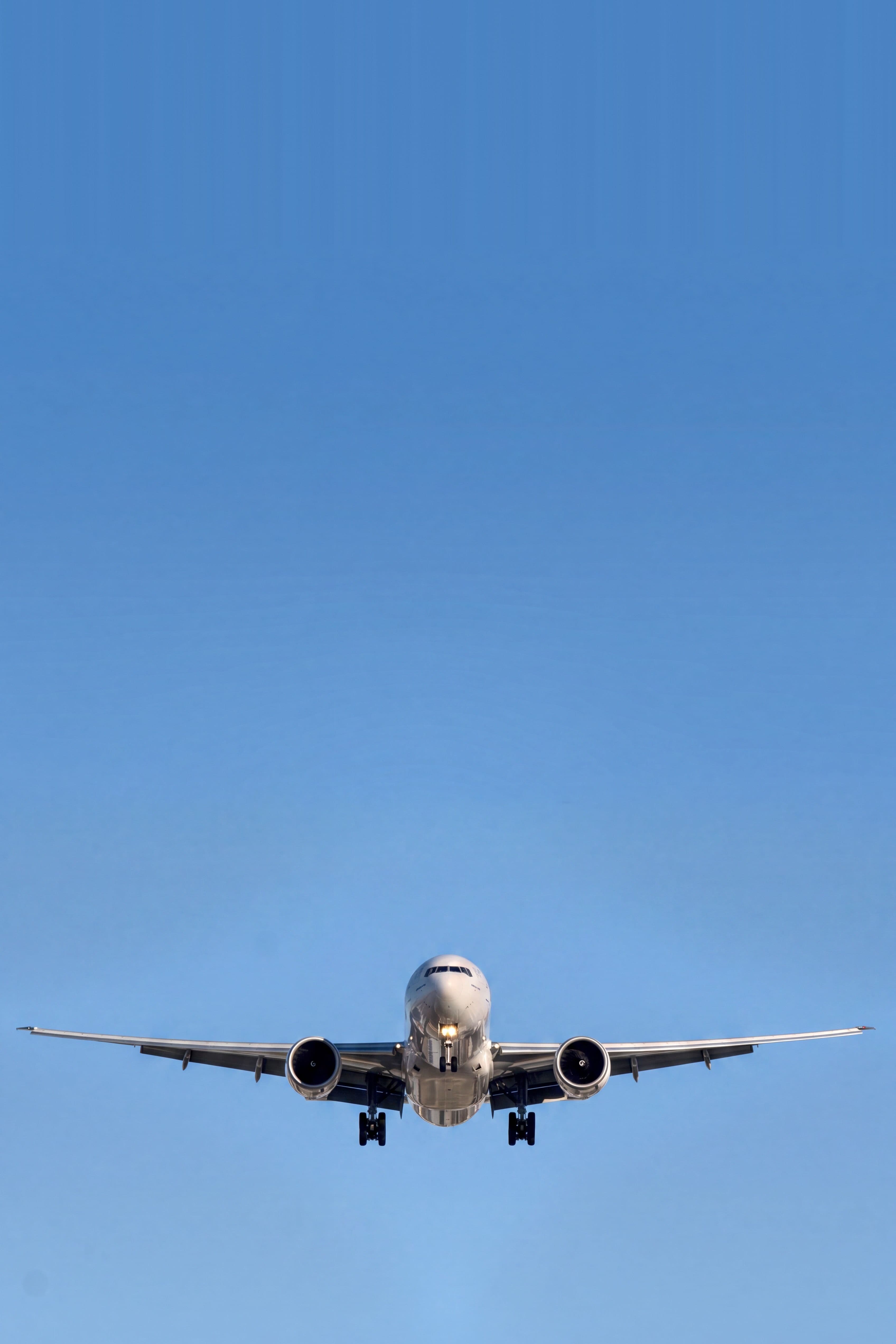 Verkehrsflugzeug im Landeanflug mit ausgefahrenem Fahrwerk vor wolkenlosem blauem Himmel
