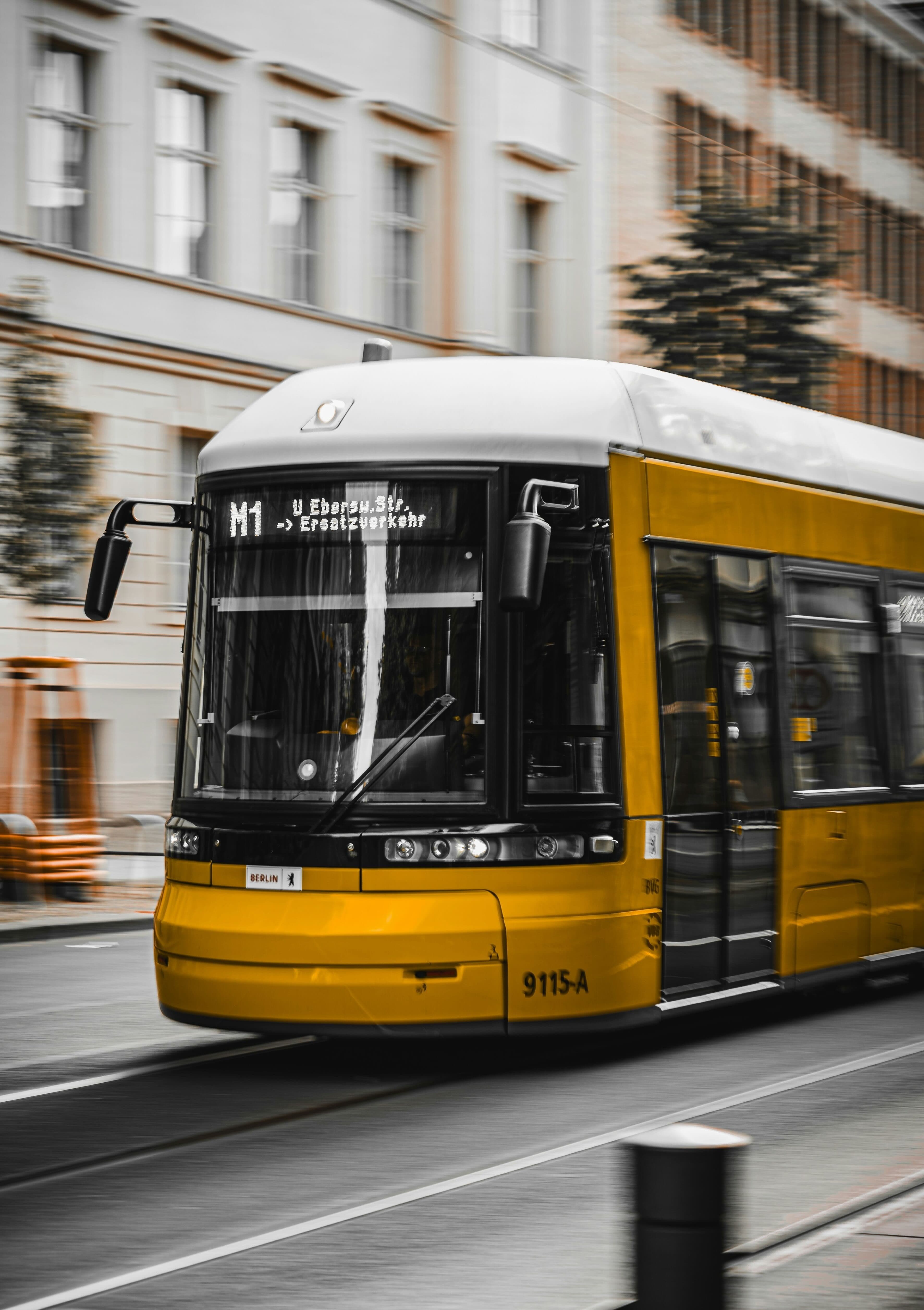 Gelbe Berliner Straßenbahn fährt an einer hellen Altbaufassade vorbei
